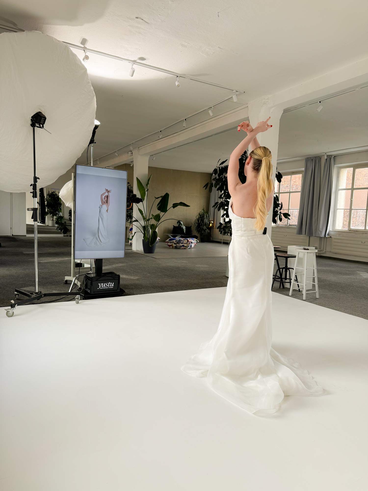 Eine Kundin im yustu Studio. Die Fernbedienung ist hinten an ihrer Taille am Kleid befestigt; eine gestrichelte Linie zeigt darauf.